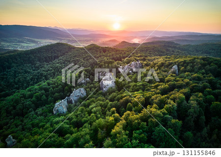 Breathtaking sunset casts golden glow over vast, dense forest, with rugged rock formations peeking through trees. Dovbush Rocks, Carpathian mountains, Ukraine. Breathtaking sunset casts golden glow over vast, dense forest, with rugged rock formations peeking through trees. Dovbush Rocks, Carpathian mountains, Ukraine. 131155846