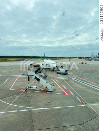 Busy airport scene with an airplane ready for boarding and ground crew preparing for departure during a cloudy day Busy airport scene with an airplane ready for boarding and ground crew preparing for departure during a cloudy day 131155905