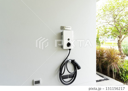 Electric car charging station mounted on white wall. Electric car charging station mounted on white wall. 131156217