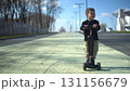 A child joyfully riding their scooter on a sunny day in a beautiful park filled with nature 131156679