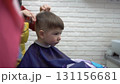 toddler smiling in barber chair while getting a haircut 131156681