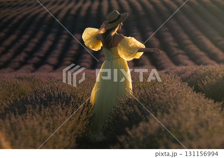 Lavender Dress Woman Provence France: Golden hour photoshoot, woman in yellow dress poses amidst blooming lavender fields in Provence, France, capturing picturesque summer scene. 131156994