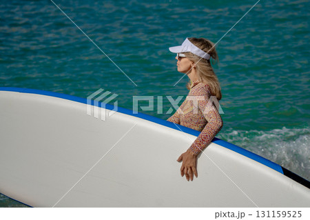Woman Paddleboard Ocean: Blonde woman carrying board in turquoise water on sunny day for sport. 131159525