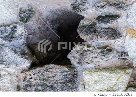 hole in the stone wall of an old house close-up of gray and black stone 131160268
