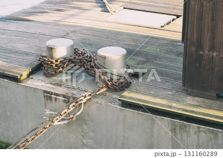mooring pole with rope and chain around it on the pier mooring pole with rope and chain around it on the pier 131160289