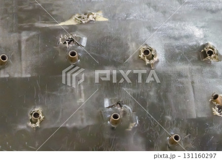 old bulletproof vest riddled with large-caliber weapons with stuck shells close-up 131160297