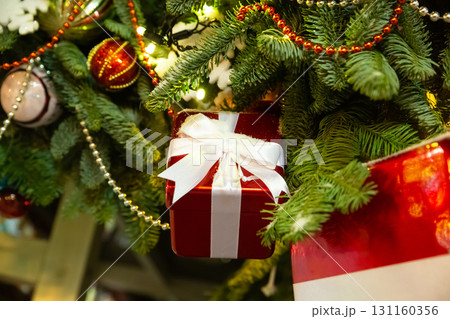 red giftbox, a small box on the background of a decorated Christmas tree red giftbox, a small box on the background of a decorated Christmas tree 131160356