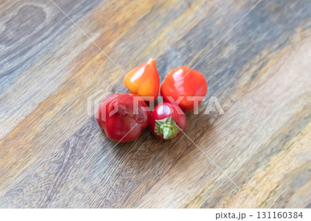 4 chili peppers lying on wooden background 131160384