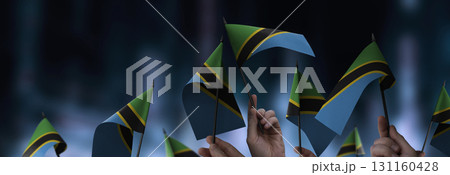 Tanzania flags in their hands on a blurred urban background Tanzania flags in their hands on a blurred urban background 131160428
