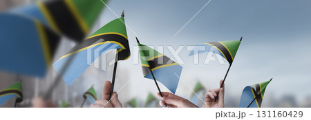 Tanzania flags in their hands on a blurred urban background 131160429