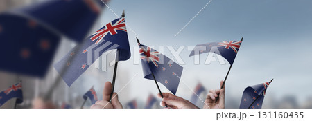 New Zealand flags in their hands on a blurred urban background 131160435