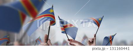 Democratic Republic of the Congo flags in their hands on a blurred urban background Democratic Republic of the Congo flags in their hands on a blurred urban background 131160441