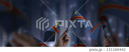 Democratic Republic of the Congo flags in their hands on a blurred urban background Democratic Republic of the Congo flags in their hands on a blurred urban background 131160442