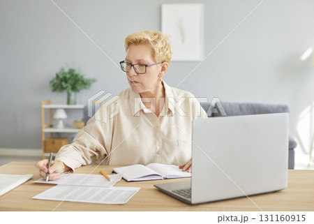 Senior accountant woman sitting on workplace at the desk with laptop working with charts 131160915