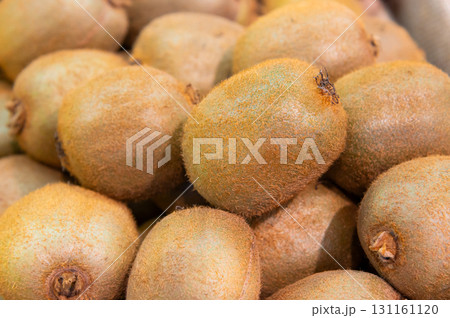 A pile of fresh and ripe kiwis close-up. A neat pyramid of beautiful fruits in a store. The texture of the peel is visible 131161120