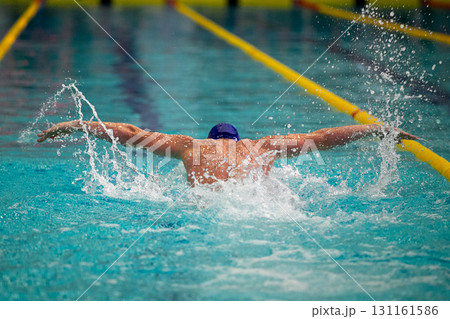 Rear view swimmer performing butterfly stroke at swimming competition 131161586