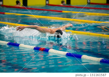 Swimmer performing butterfly stroke at swimming competition 131161587