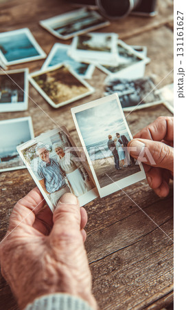 室内の木製テーブルで海辺の思い出写真を眺める老夫婦 131161627