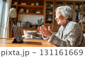 在宅リビングの高齢女性がタブレットでオンライン通話中昼間 131161669