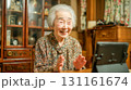 室内リビングで日中タブレットとオンライン通話する高齢女性 131161674