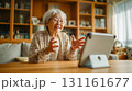 自宅のリビングで昼間タブレットとビデオ通話する高齢女性 131161677