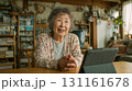 自宅リビングで一人の高齢女性がタブレット使い会話昼 131161678