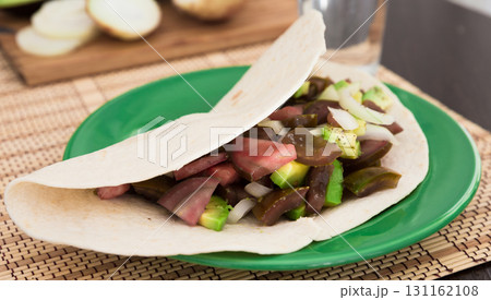 salad of black tomatoes, avocado and onions in Italian tortilla on green plate 131162108