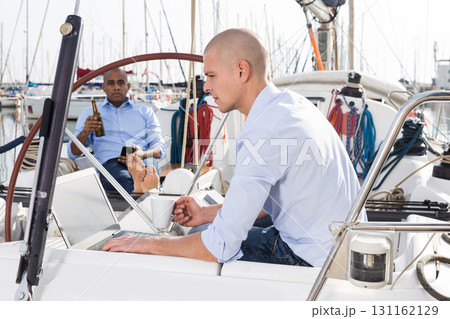 caucasian guy with laptop on private yachts in the seaport 131162129