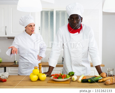 Strict female chef reprimanding male colleague in private kitchen Strict female chef reprimanding male colleague in private kitchen 131162133