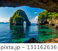 View of rock formation and green trees in the blue sea with mountain and blue sky in the background. 131162636