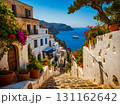 View of white houses with a stone steps and colorful flowers in clay pot on the shores of the blue sea. 131162642