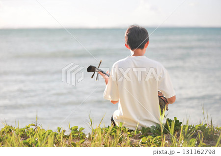 海で三線を奏でる少年 131162798