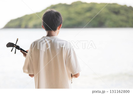 海で三線を奏でる少年 131162800
