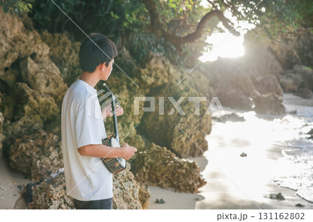 海岸で三線を奏でる少年 131162802