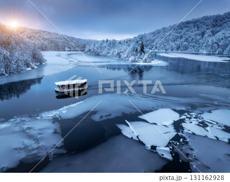 Aerial drone view of boat in frozen lake at sunset in winter 131162928