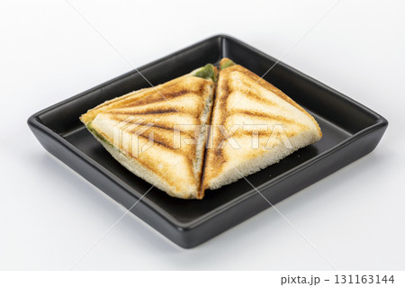 Toasted triangle sandwich with pandan custard filling on black plate, golden brown bread, sweet Asian snack food. Toasted triangle sandwich with pandan custard filling on black plate, golden brown bread, sweet Asian snack food. 131163144