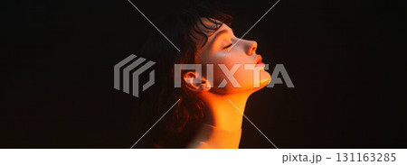 serene side profile of young woman illuminated by warm light 131163285