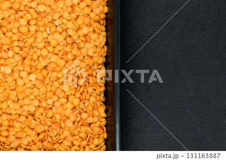 Red Lentil Grains in Black Plate on Black Stone Background Surface with Free Space Splitted in Half 131163887