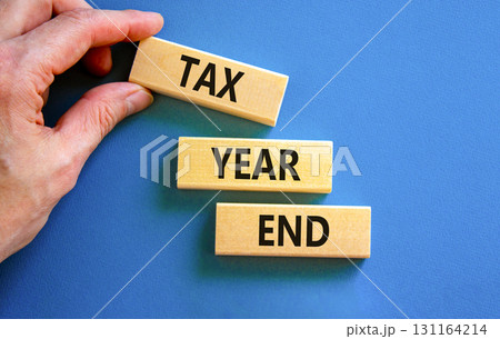 Tax year end symbol. Concept words Tax year end on beautiful wooden blocks. Beautiful blue background. Businessman hand. Business tax year end concept. Copy space. 131164214