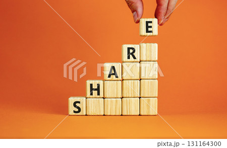Share symbol. Concept word Share on beautiful wooden blocks. Beautiful orange table orange background. Businessman hand. Business lifestyle share concept. Copy space. 131164300