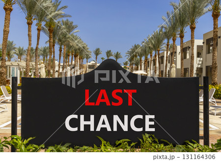 Last chance symbol. Concept word Last chance on beautiful black road sign. Beautiful palm trees and blue sky background. Business last chance concept. Copy space. 131164306