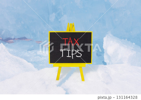 Tax tips symbol. Concept word Tax tips on beautiful black blackboard. Beautiful Baikal blue ice and snow background. Black blackboard. Business tax tips concept. Copy space. 131164328