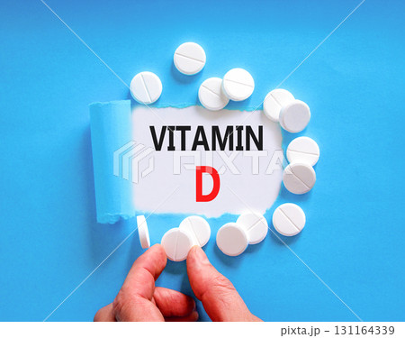 Vitamin D symbol. Concept words Vitamin D on beautiful white paper. White pills tablets. Doctor's hand. Beautiful blue background. Medical healthy lifestyle Vitamin D concept. 131164339