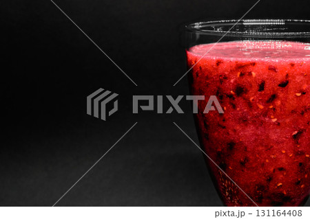 Side glass view of black currant red color cocktail in black background surface 131164408