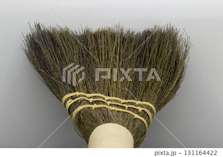 Straw broom on grey background Straw broom on grey background 131164422