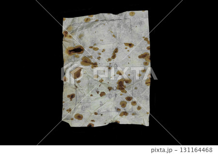 Very old and aged white paper sheet with brown spots on it isolated on black background surface 131164468
