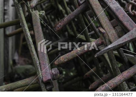 Very old and rusty harrows places near barn wall at countryside 131164477