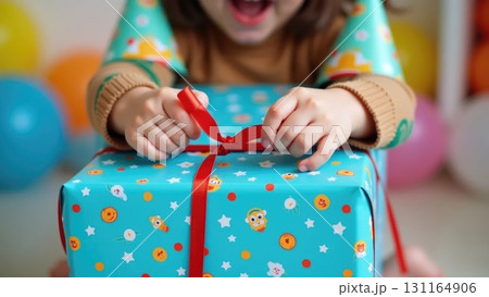 Child's Hands Unwrapping a Colorful Birthday Gift with Confetti Background 131164906