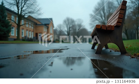 Empty Schoolyard After Rain with Flag Reflection in Puddle and Overturned Bench 131164936