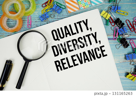 Quality, Diversity, Relevance text on a paper surrounded by office supplies and magnifying glass on a blue wooden surface 131165263